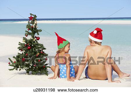 Boy And Girl Sitting On Beach With Christmas Tree And Hat View Large Photo Image Stock Photo - Boy And Girl Sitting On Beach With Christmas Tree And Hat. Fotosearch