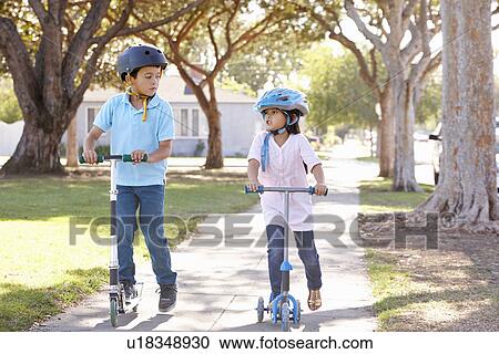 Boy And Girl Wearing Safety Helmets And Riding Scooters View Large Photo Image Stock Image - Boy And Girl Wearing Safety Helmets And Riding Scooters. Fotosearch