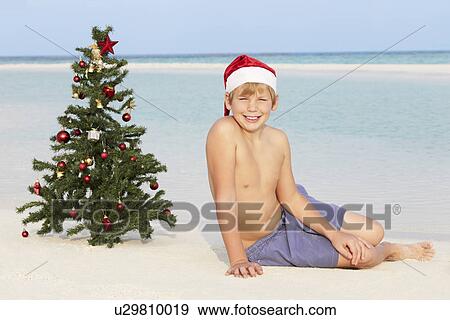 Boy Sitting On Beach With Christmas Tree And Hat View Large Photo Image Stock Photo - Boy Sitting On Beach With Christmas Tree And Hat. Fotosearch