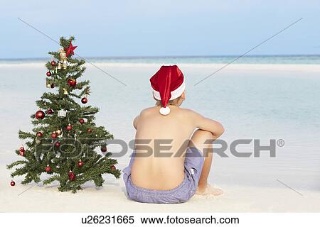 Boy Sitting On Beach With Christmas Tree And Hat View Large Photo Image Stock Photography - Boy Sitting On Beach With Christmas Tree And Hat. Fotosearch