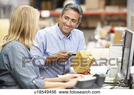 Stock Photograph - Business Colleagues Working At Desk In Warehouse. Fotosearch