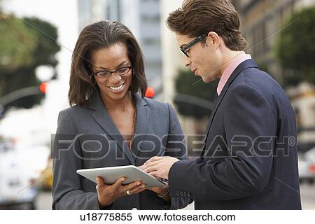 Stock Photography - Businessman And Businesswoman Using Digital Tablet Outside . Fotosearch