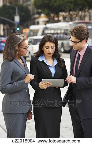 Picture - Businessman And Businesswomen Using Digital Tablet Outside . Fotosearch