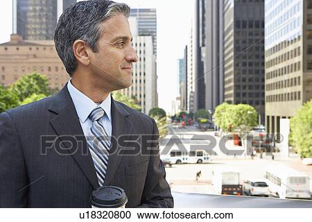 Stock Image - Businessman Drinking Takeaway Coffee Outside Office. Fotosearch
