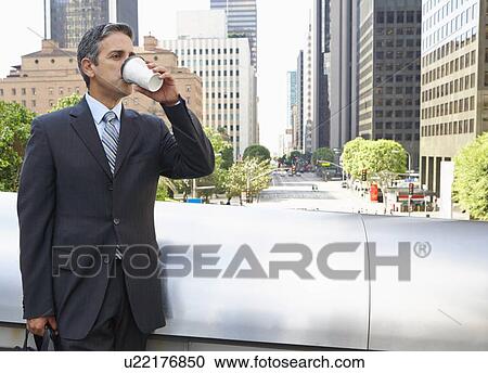 Stock Image - Businessman Drinking Takeaway Coffee Outside Office. Fotosearch