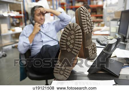 Businessman Putting Feet Up On Desk In Warehouse View Large Photo Image Stock Photo - Businessman Putting Feet Up On Desk In Warehouse. Fotosearch