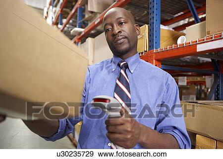 Businessman Scanning Package In Warehouse View Large Photo Image Stock Photo - Businessman Scanning Package In Warehouse. Fotosearch