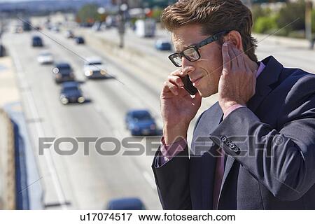 Businessman Speaking On Mobile Phone By Noisy Freeway View Large Photo Image Stock Photo - Businessman Speaking On Mobile Phone By Noisy Freeway. Fotosearch