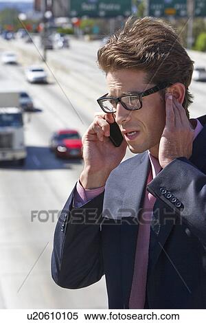 Stock Photography - Businessman Speaking On Mobile Phone By Noisy Freeway. Fotosearch