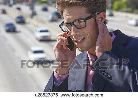 Stock Photography - Businessman Speaking On Mobile Phone By Noisy Freeway. Fotosearch