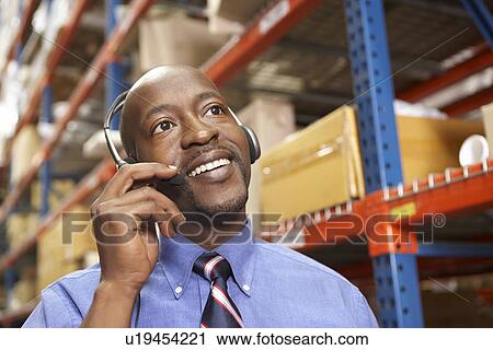 Businessman Using Headset In Distribution Warehouse View Large Photo Image Stock Image - Businessman Using Headset In Distribution Warehouse. Fotosearch