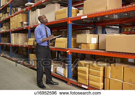Stock Photograph - Businessman With Clipboard In Warehouse. Fotosearch