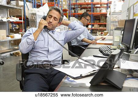 Stock Photography - Businessman Working At Desk In Warehouse. Fotosearch