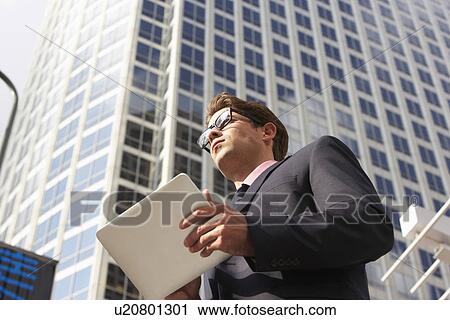 Stock Image - Businessman Working On Tablet Computer Outside Office. Fotosearch
