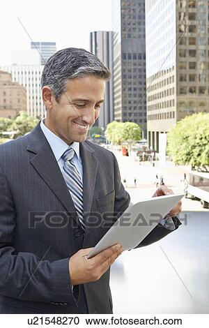 Stock Image - Businessman Working On Tablet Computer Outside Office. Fotosearch