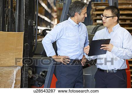 Stock Photo - Businessmen Meeting By Fork Lift Truck In Warehouse. Fotosearch