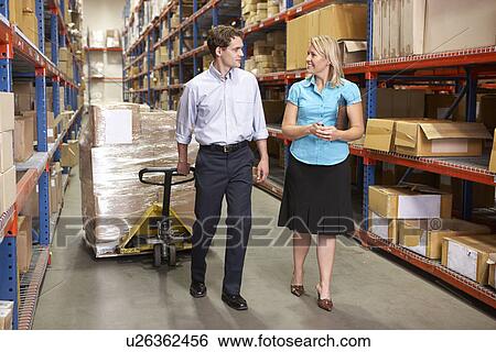 Stock Photograph - Businesswoman And Colleague In Distribution Warehouse. Fotosearch