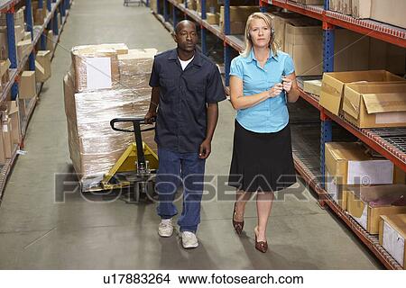 Picture - Businesswoman And Male Worker In Distribution Warehouse. Fotosearch