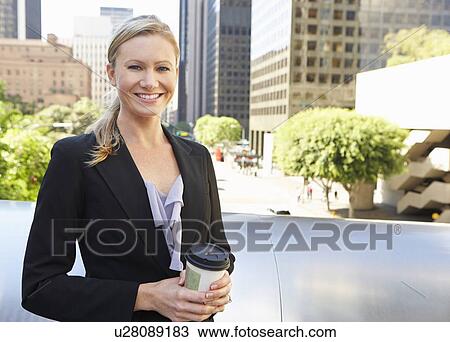 Stock Image - Businesswoman Drinking Takeaway Coffee Outside Office. Fotosearch