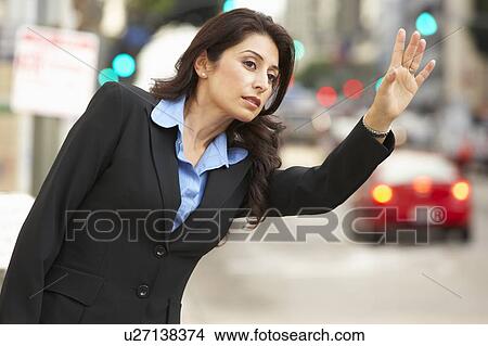 Picture - Businesswoman Hailing Taxi In Busy Street . Fotosearch