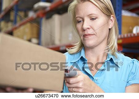 Stock Image - Businesswoman Scanning Package In Warehouse. Fotosearch
