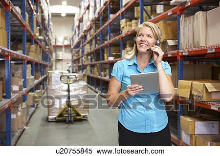 Stock Photography - Businesswoman Using Digital Tablet In Distribution Warehouse. Fotosearch
