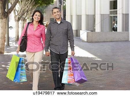 Stock Photo - Couple Carrying Shopping Bags On City Street. Fotosearch