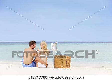 Stock Image - Couple On Beach With Luxury Champagne Picnic. Fotosearch