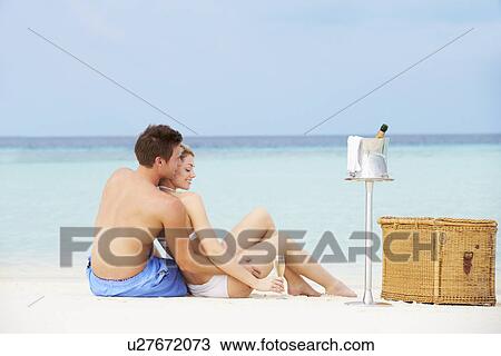 Stock Image - Couple On Beach With Luxury Champagne Picnic. Fotosearch