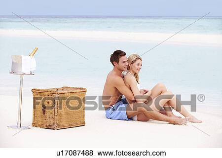 Stock Photo - Couple On Beach With Luxury Champagne Picnic. Fotosearch