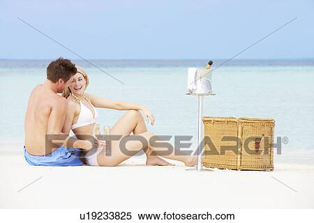 Stock Photography - Couple On Beach With Luxury Champagne Picnic. Fotosearch