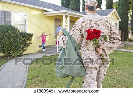 Stock Image - Family Welcoming Husband Home On Army Leave. Fotosearch
