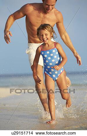 Picture - Father And Daughter Having Fun In Sea On Beach Holiday. Fotosearch