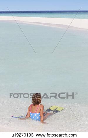 Stock Image - Girl Sitting On Beach Wearing Snorkel And Flippers. Fotosearch