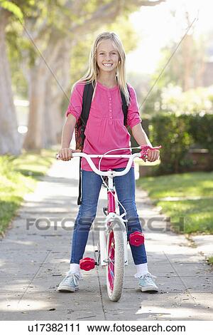 Stock Image - Girl Wearing Rucksack Cycling To School. Fotosearch