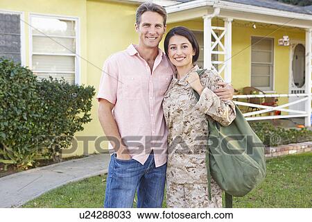 Stock Image - Husband Welcoming Wife Home On Army Leave. Fotosearch