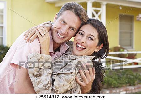 Stock Image - Husband Welcoming Wife Home On Army Leave. Fotosearch