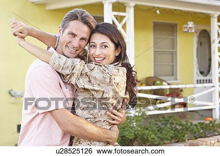 Stock Photograph - Husband Welcoming Wife Home On Army Leave. Fotosearch
