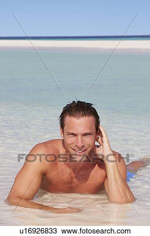 Stock Image - Man Relaxing In Sea On Beach Tropical Beach. Fotosearch