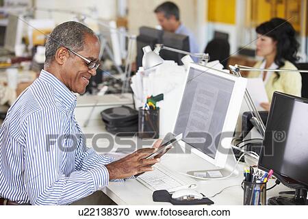 Man Using Digital Tablet In Busy Creative Office View Large Photo Image Stock Image - Man Using Digital Tablet In Busy Creative Office. Fotosearch