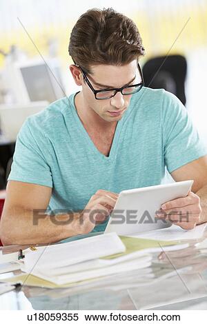 Stock Photography - Man Using Digital Tablet In Busy Creative Office. Fotosearch