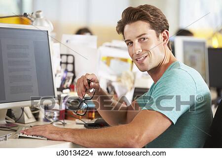Man Working At Desk In Busy Creative Office View Large Photo Image Picture - Man Working At Desk In Busy Creative Office. Fotosearch