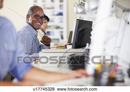 Man Working At Desk In Busy Creative Office View Large Photo Image Stock Photo - Man Working At Desk In Busy Creative Office. Fotosearch
