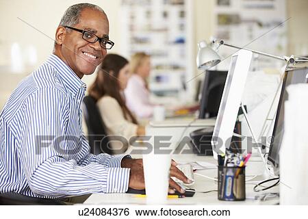 Man Working At Desk In Busy Creative Office View Large Photo Image Stock Photograph - Man Working At Desk In Busy Creative Office. Fotosearch