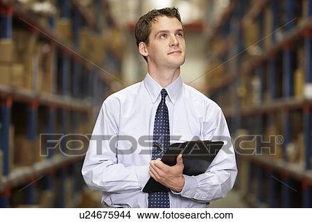 Picture - Manager In Warehouse With Clipboard. Fotosearch