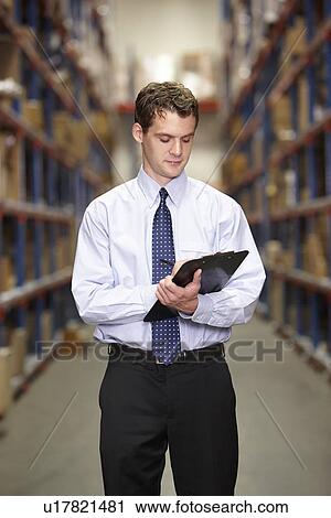 Stock Image - Manager In Warehouse With Clipboard. Fotosearch