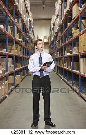 Stock Image - Manager In Warehouse With Clipboard. Fotosearch