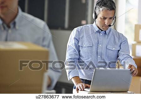 Manager Using Headset In Distribution Warehouse View Large Photo Image Stock Photo - Manager Using Headset In Distribution Warehouse. Fotosearch
