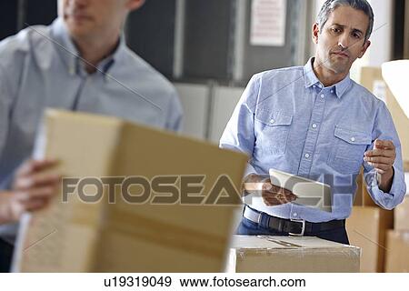 Stock Photo - Manager Using Tablet Computer In Distribution Warehouse. Fotosearch