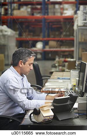 Stock Photography - Manager Working At Desk In Warehouse. Fotosearch